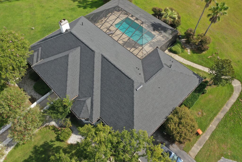 Aerial view of shingle roof installation on home with pool