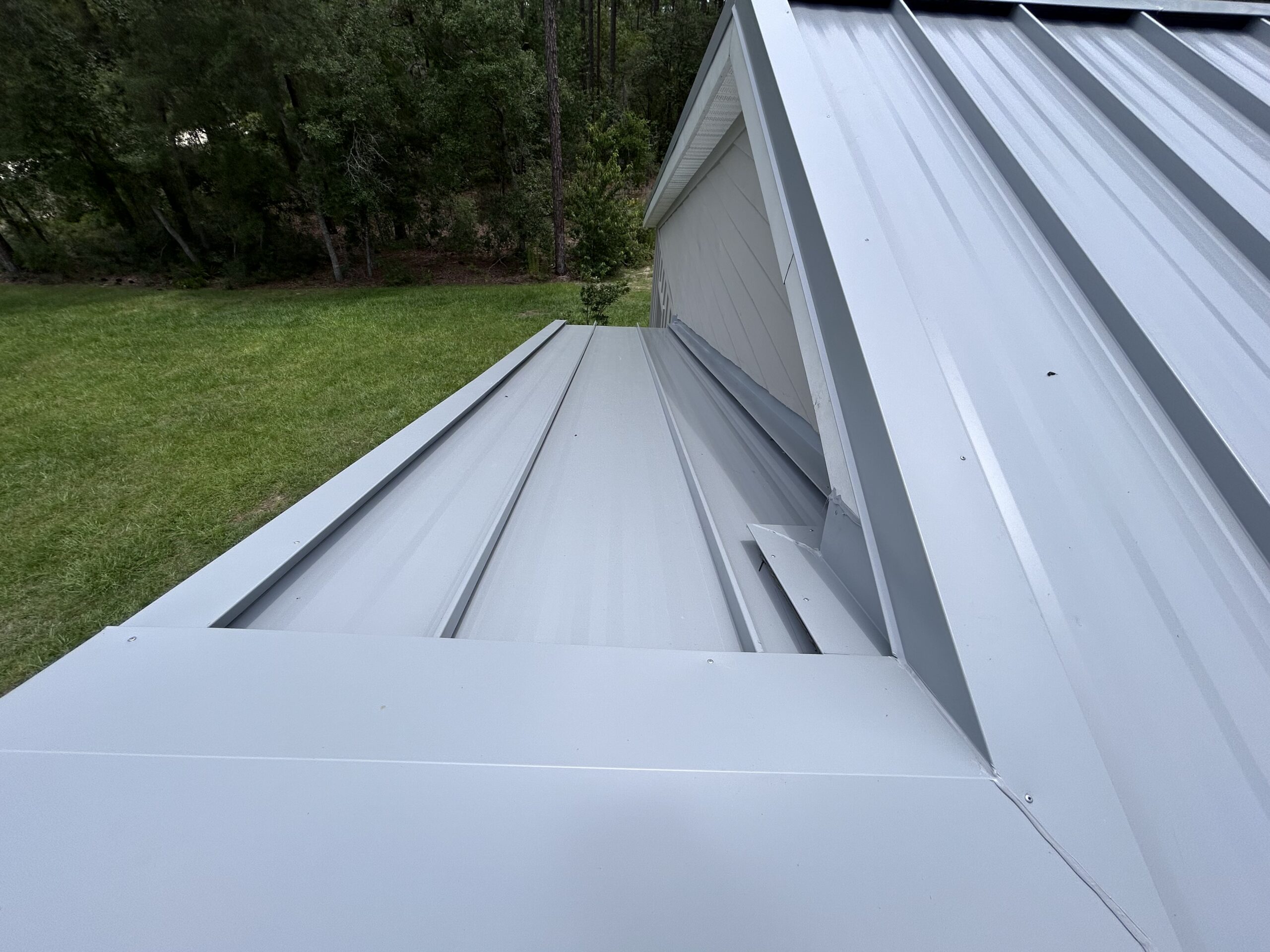 Close-up of gray standing seam metal roof ridge and hip detail showing clean panel installation by Southern Pro Roofing